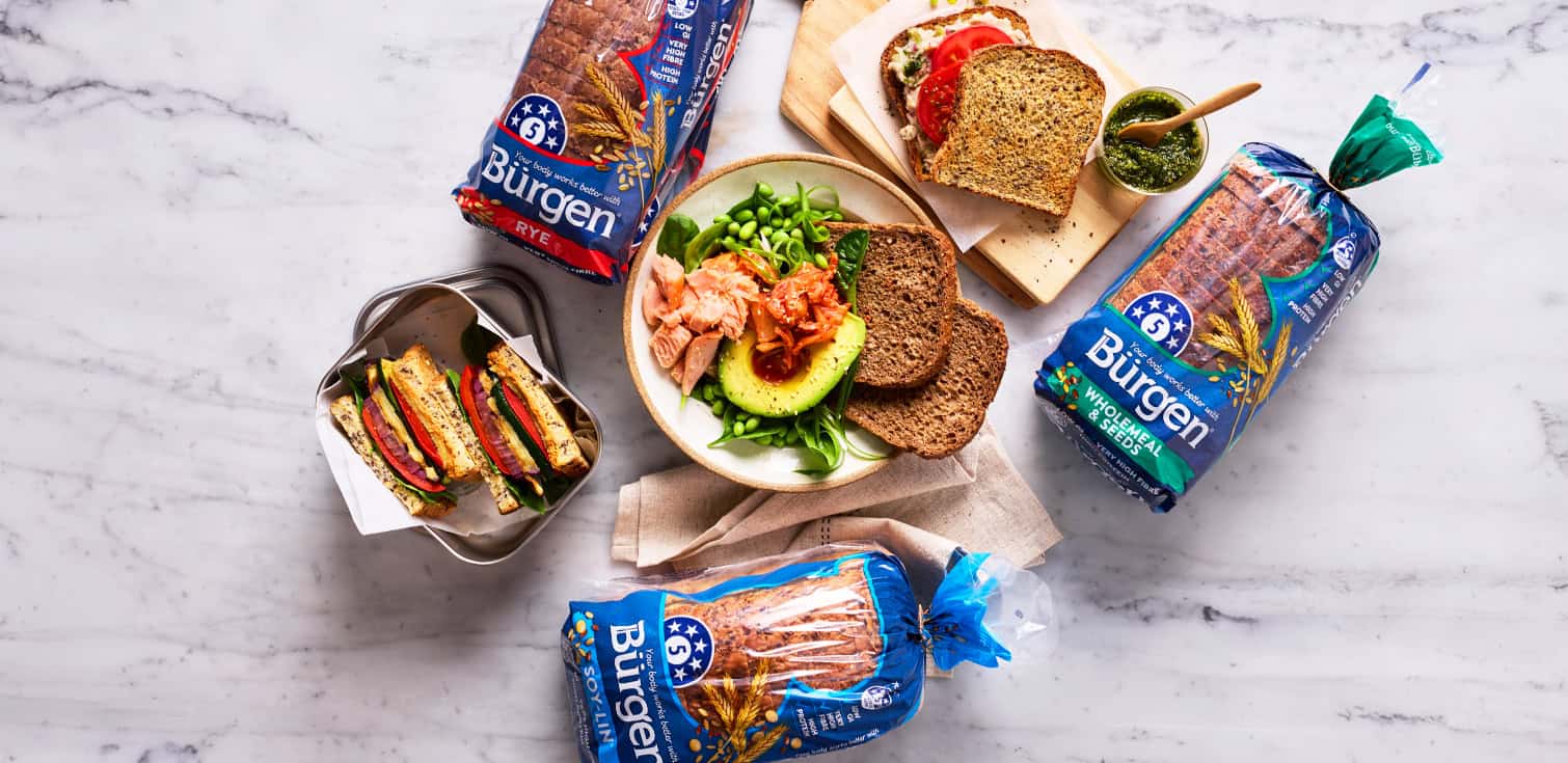 Burgen bread loaves with sandwiches, salad and toast served on a marble benchtop